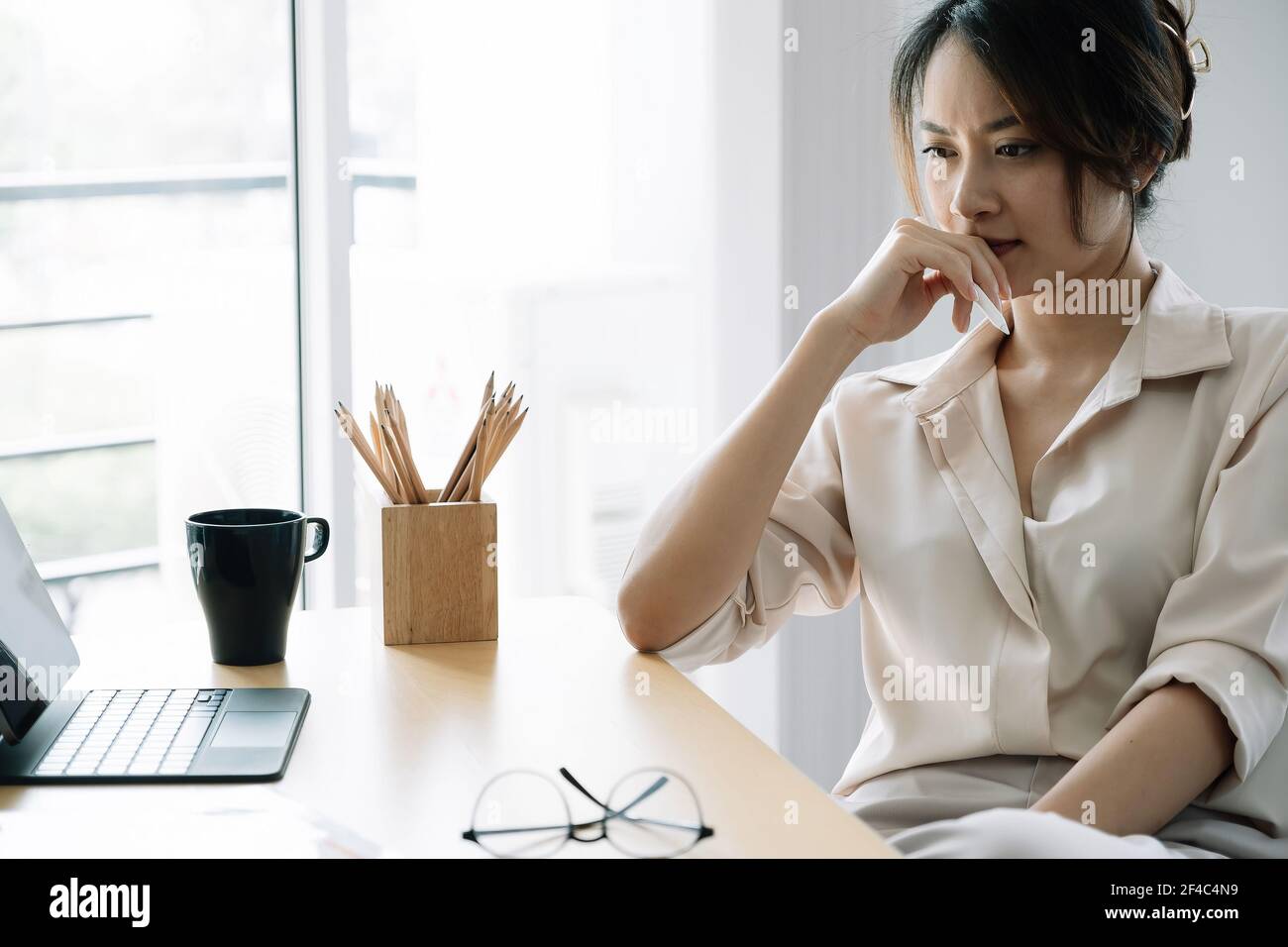 Portrait Young asian businesswoman thinking for work at her office. Stock Photo