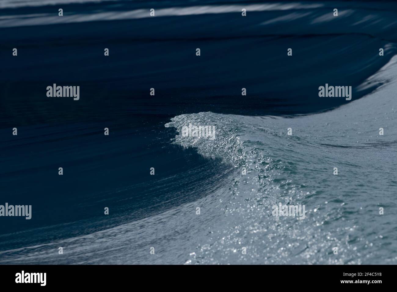 Closeup of the water at the top of a wave from a boat wake on a beautiful, clear lake. Stock Photo