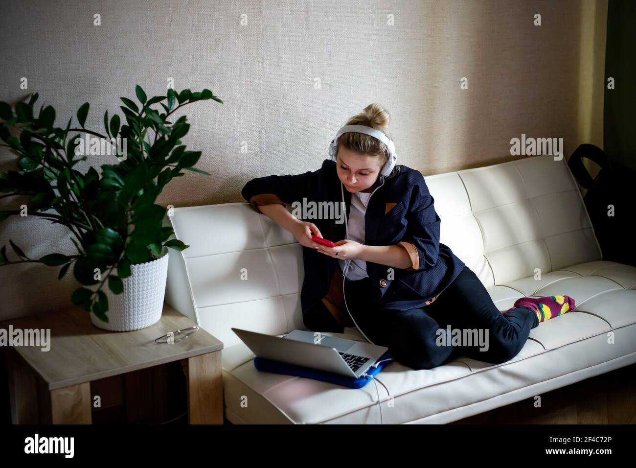 Young woman working on laptop computer while sitting at the living room ...