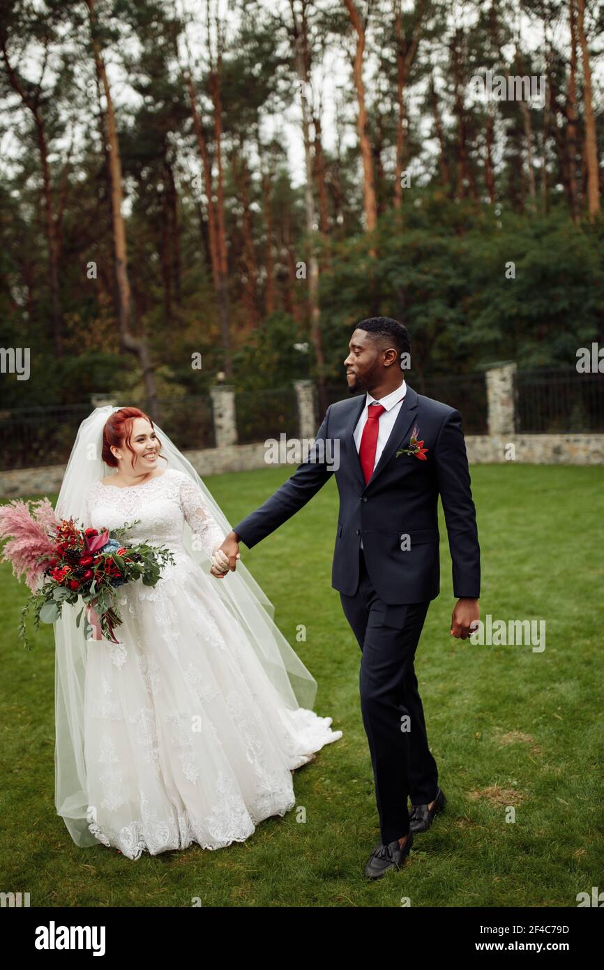 https://c8.alamy.com/comp/2F4C79D/joyful-couple-walking-at-the-park-handsome-african-american-man-with-lovely-white-woman-on-wedding-day-beautiful-bride-with-charming-groom-enjoy-2F4C79D.jpg