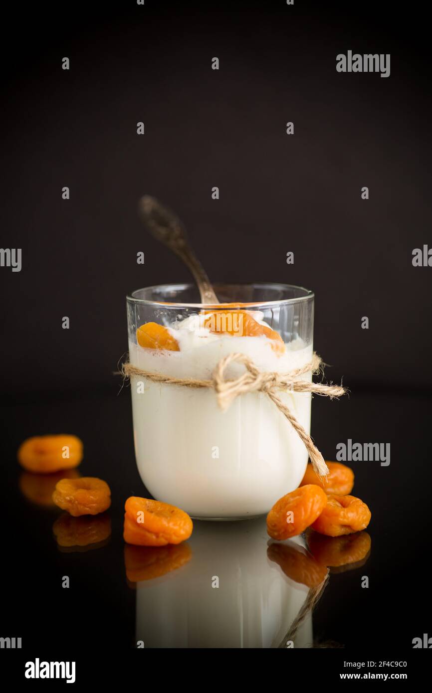 homemade sweet yogurt in a glass with dried apricots isolated on black