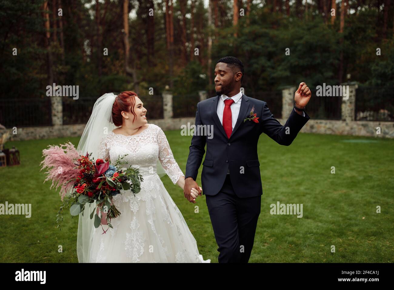 https://c8.alamy.com/comp/2F4CA1J/joyful-couple-walking-at-the-park-handsome-african-american-man-with-lovely-white-woman-on-wedding-day-beautiful-bride-with-charming-groom-enjoy-2F4CA1J.jpg