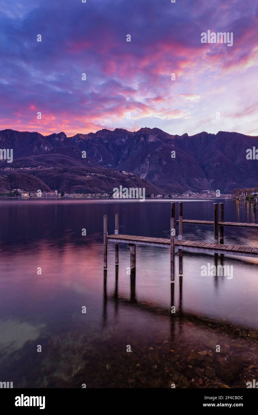 Sunrise explosion of colors in front of the Generoso Mount from a pier on Lake Ceresio, Riva San Vitale, Canton Ticino, Switzerland. Stock Photo