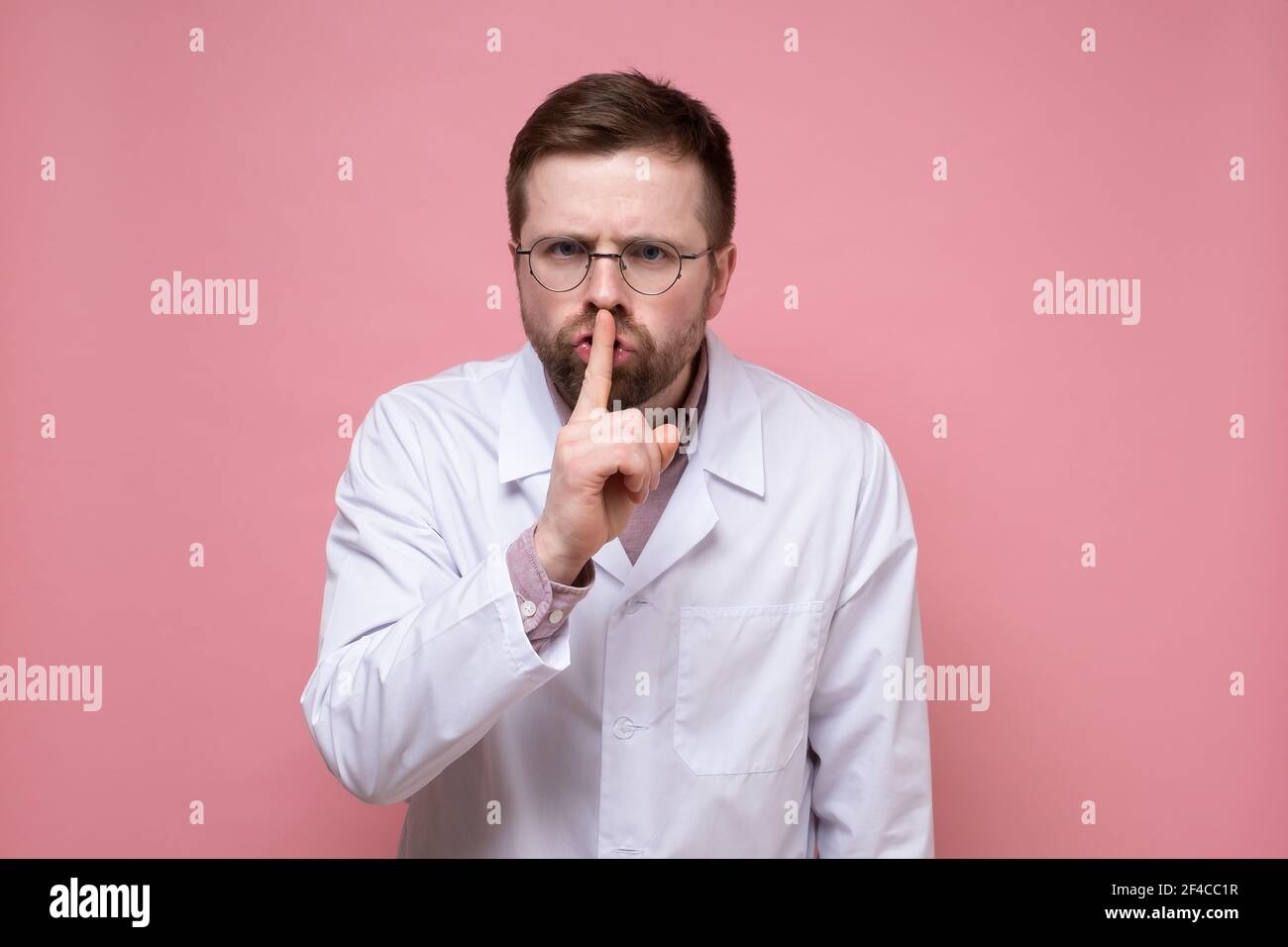 Male doctor with a stethoscope around neck put index finger to lips