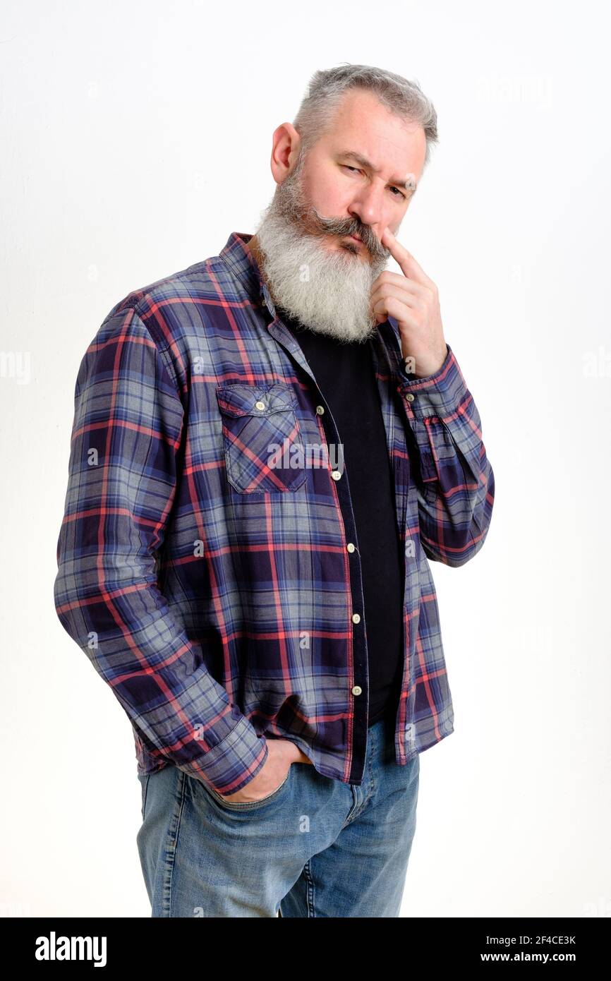 Studio portrait of pensive mature bearded man dressed in jeans and plaid shirt, looking worried, thinking about problems, white background Stock Photo