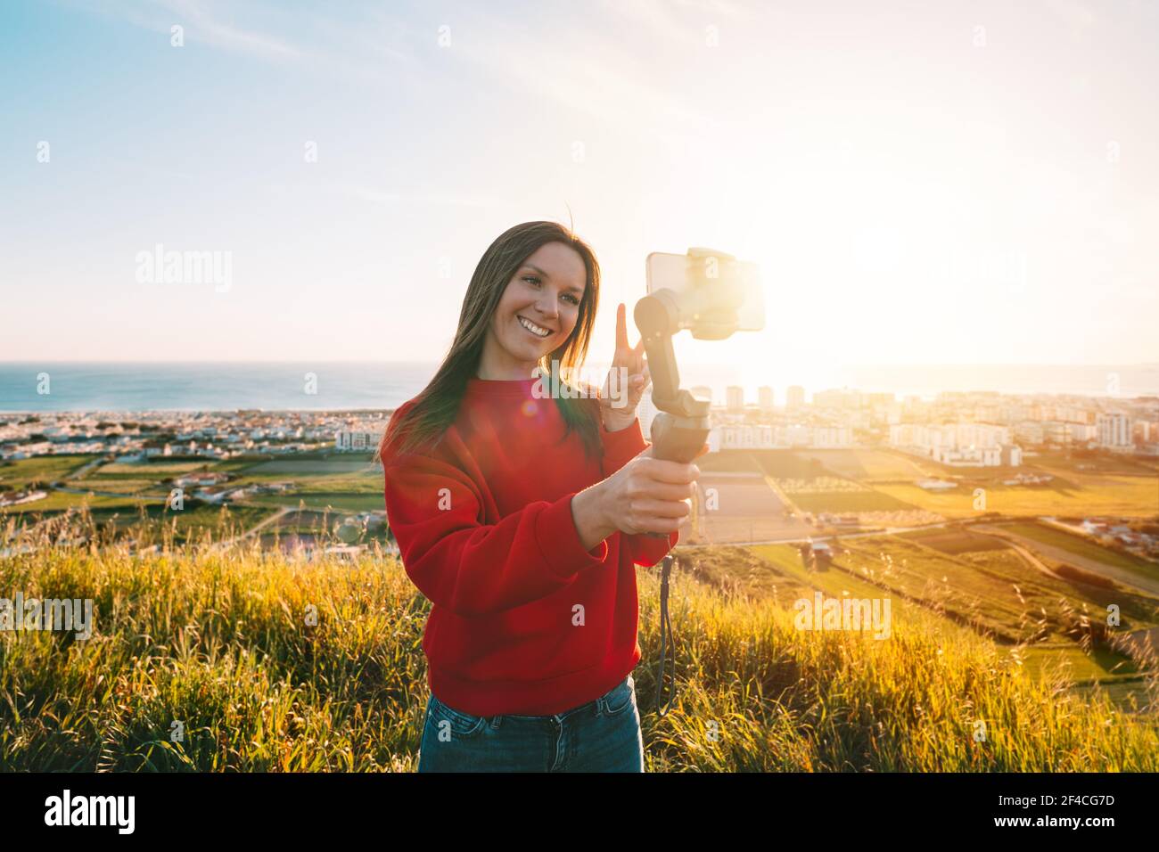 Woman with gimbal with phone and taking selfie or live streaming. Blogging Stock Photo