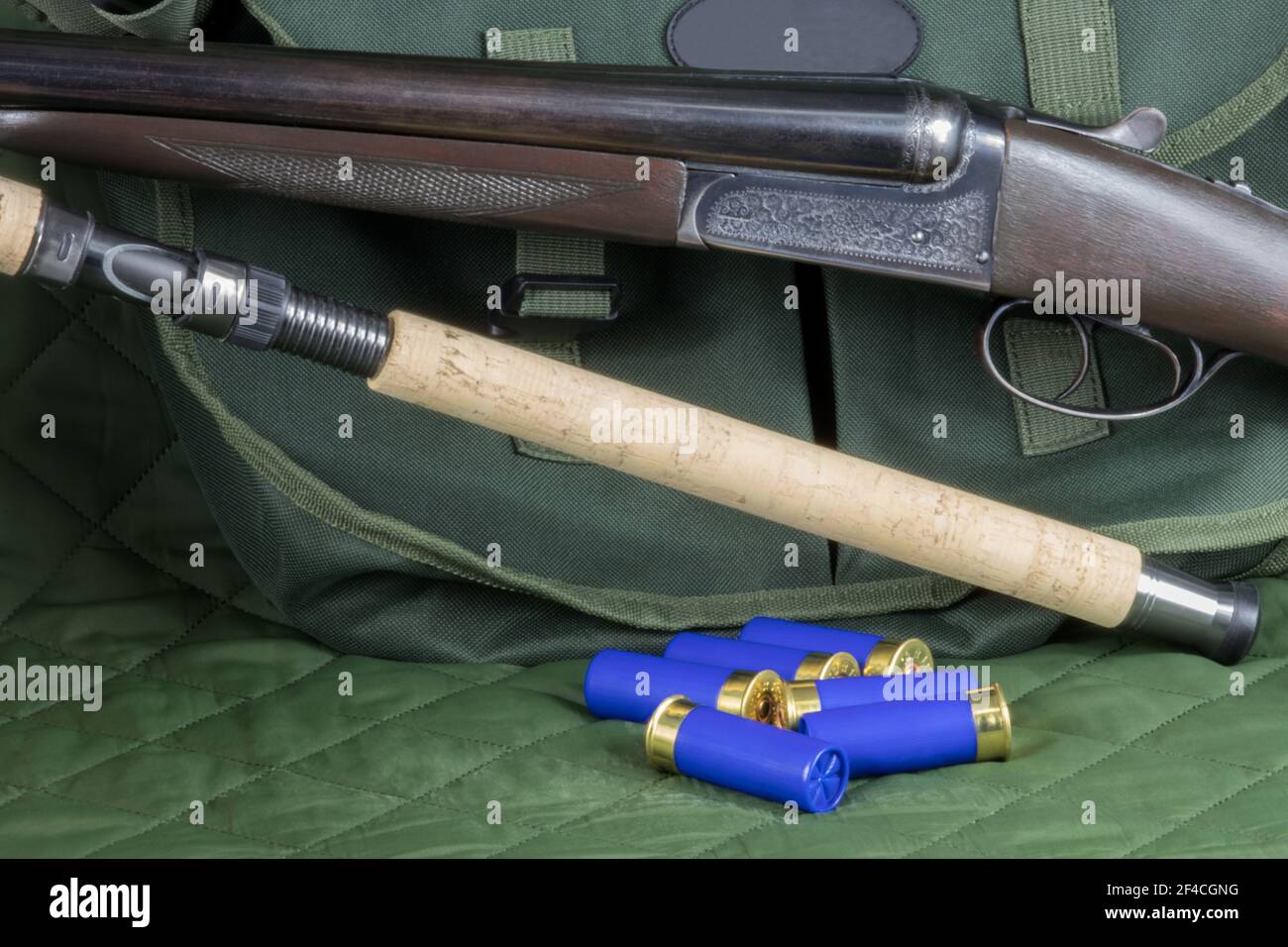 Shotgun with fishing rod and cartridges with a game bag on a green outdoor  coat Stock Photo - Alamy