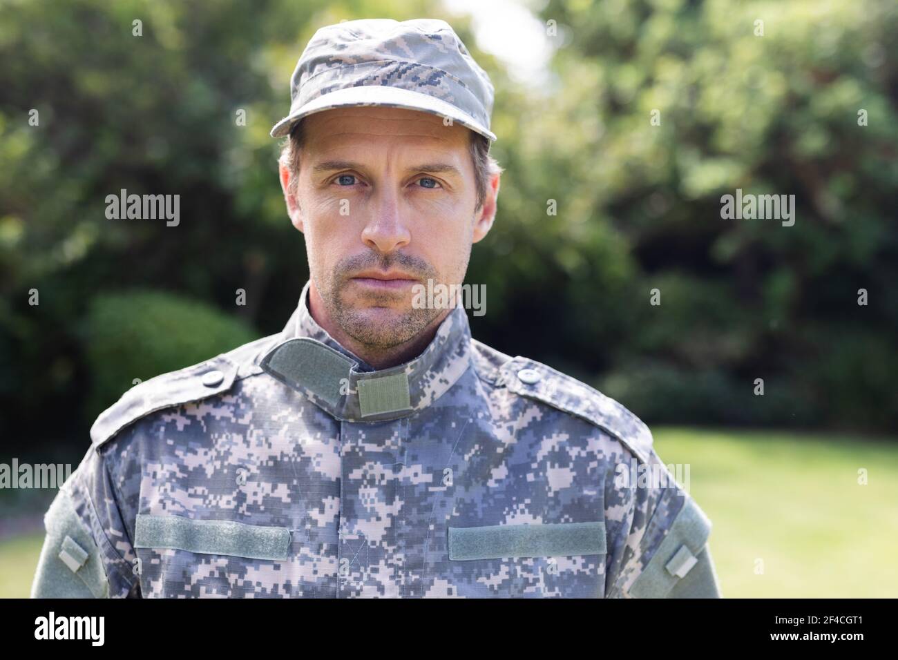 Close up portrait of caucasian male soldier wearing camo fatigues and cap standing in garden Stock Photo