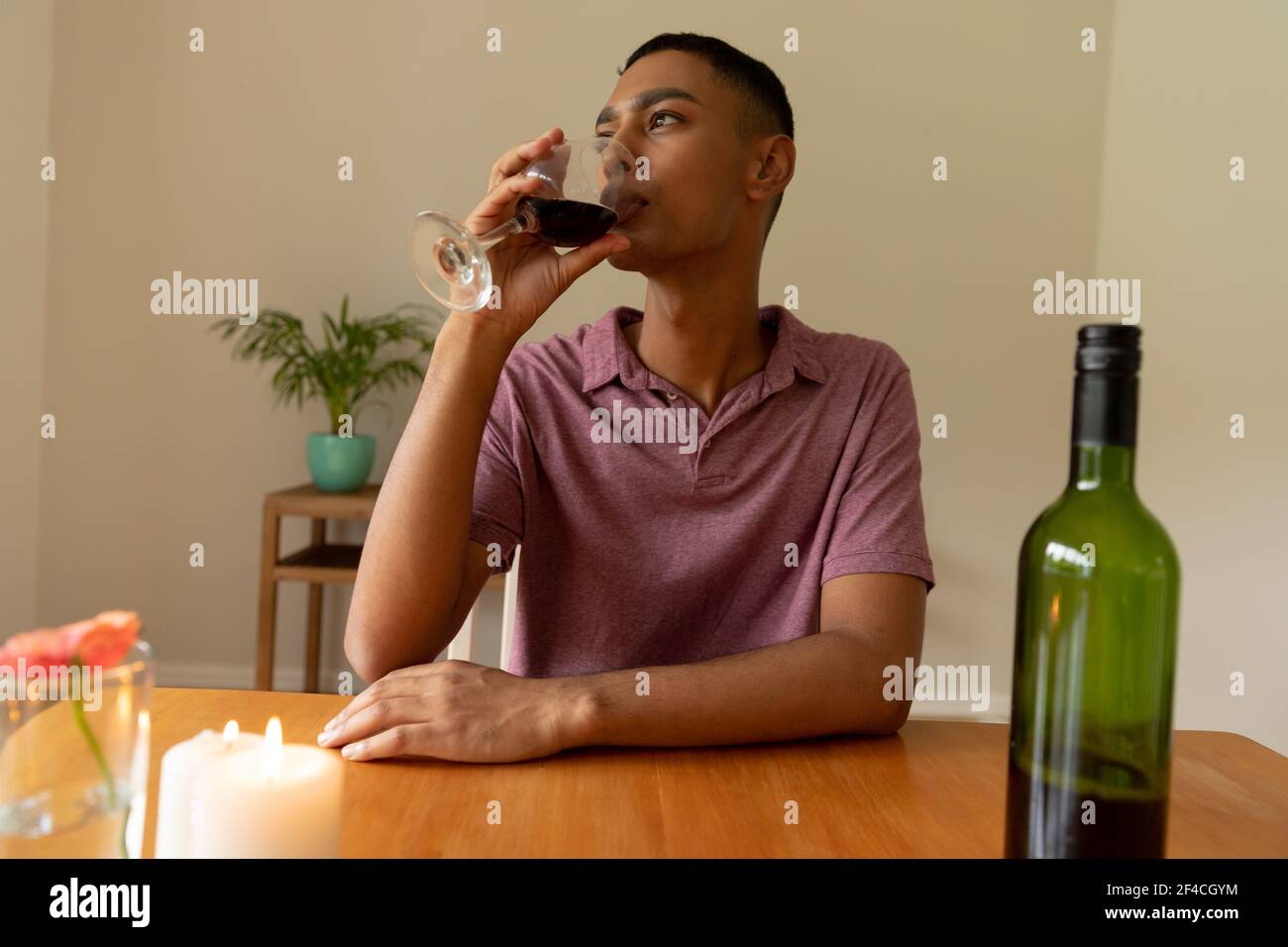 Mixed race man sitting at table and drinking wine Stock Photo