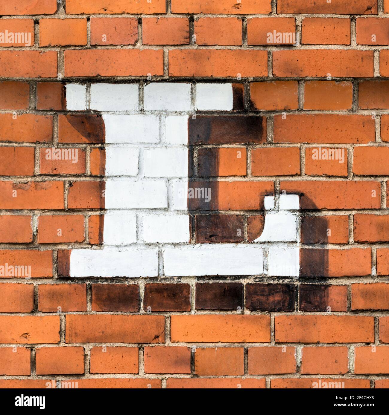 A white capital letter L painted on a red brick wall Stock Photo