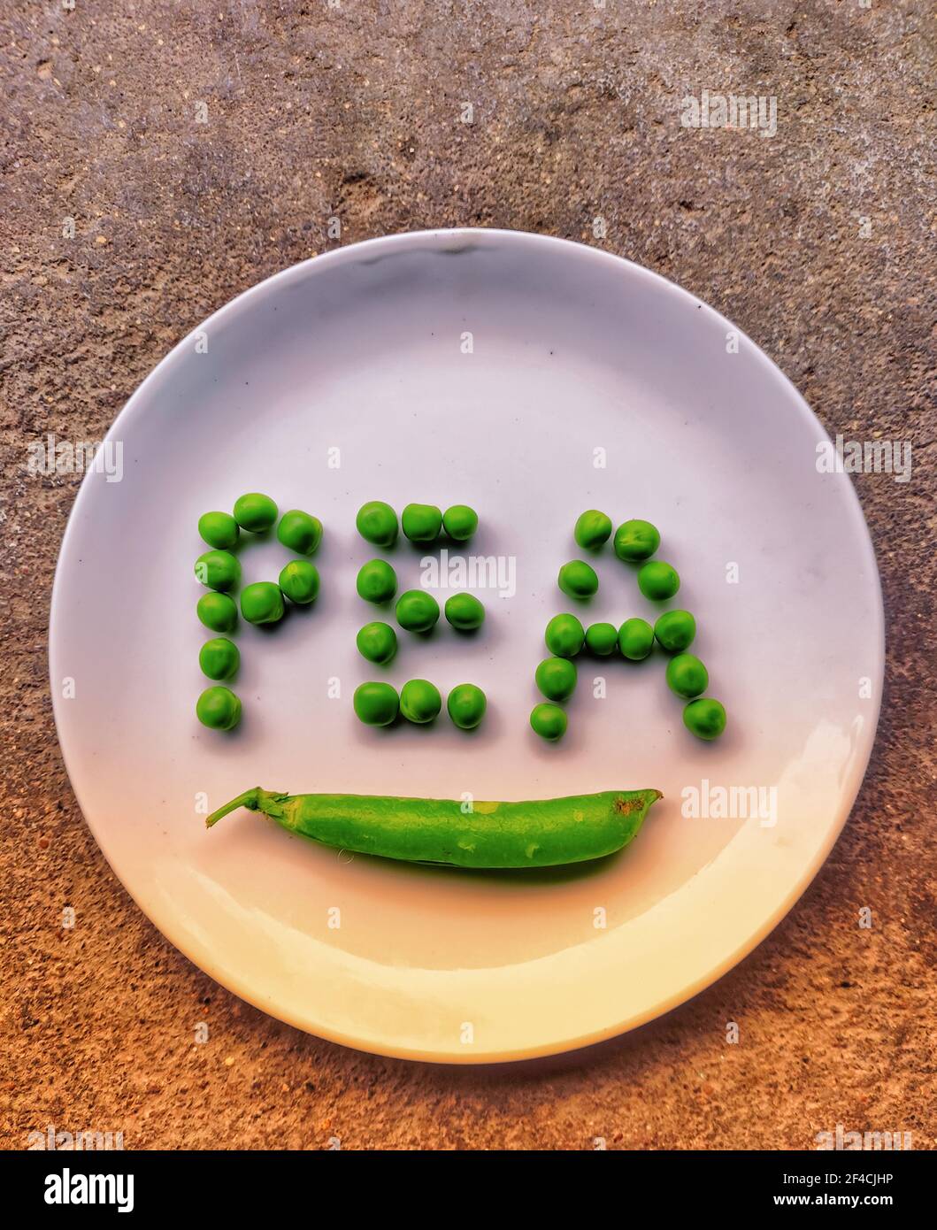 An image of fresh green peas on a plate with text pea beautiful text made with grains of pea Stock Photo