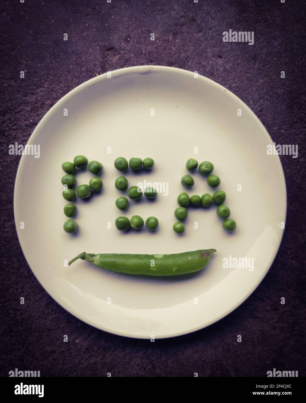 Beautiful image of fresh green peas on a plate with text from seeds this text and words are made from seeds of peas grain Stock Photo