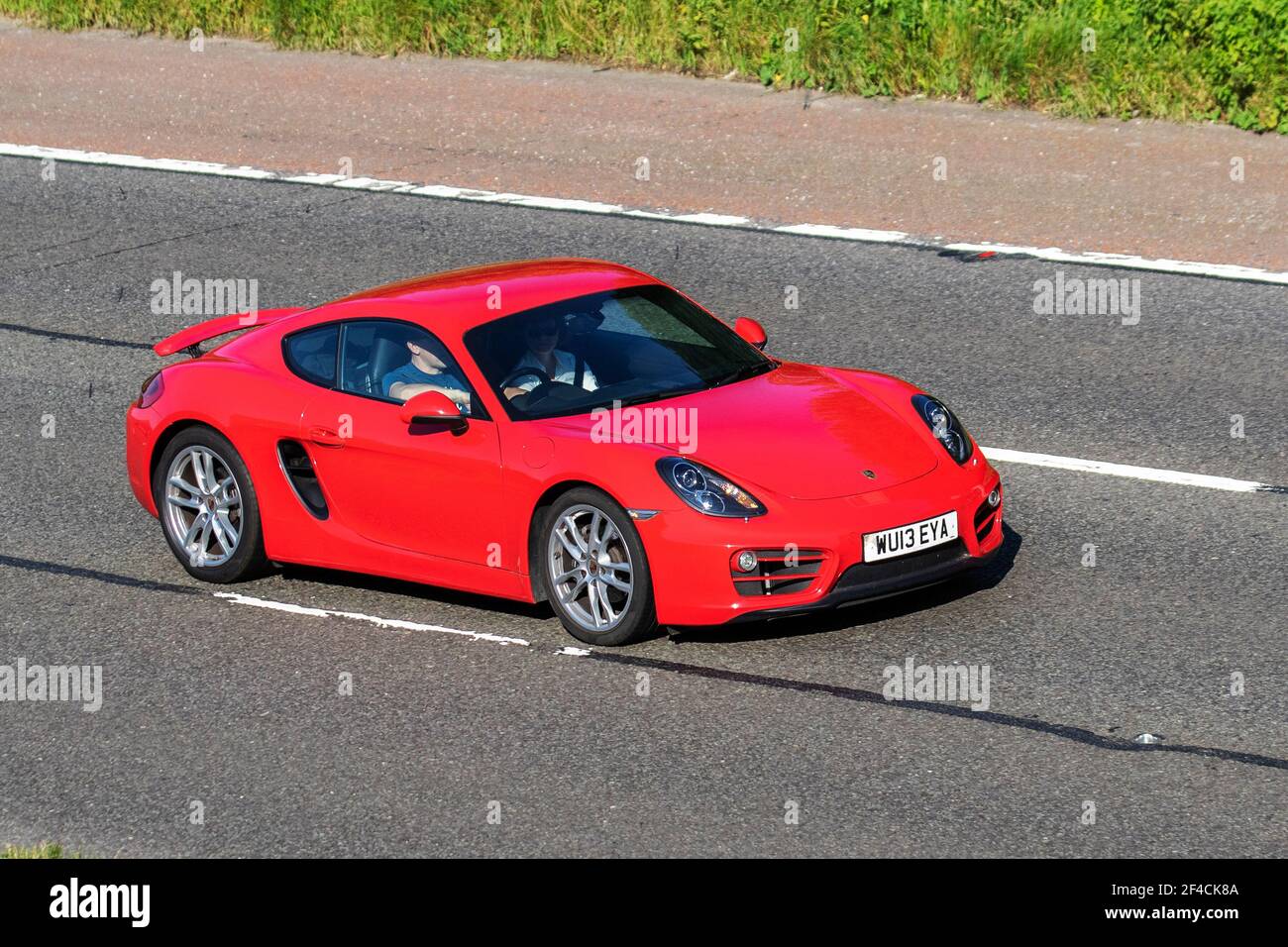2013 guards red Porsche  Cayman S-A 2706cc petrol coupe; Vehicular traffic, moving vehicles, six-cylinder engine cars, vehicle driving on UK roads, motors, motoring on the M6 highway English motorway road network Stock Photo