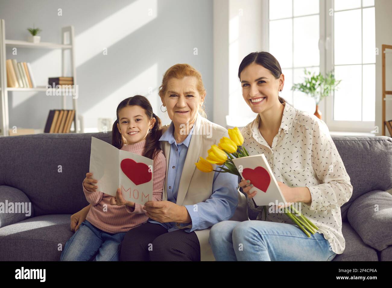 Older woman, her daughter and granddaughter exchanging gifts in honor of Mother's Day. Stock Photo