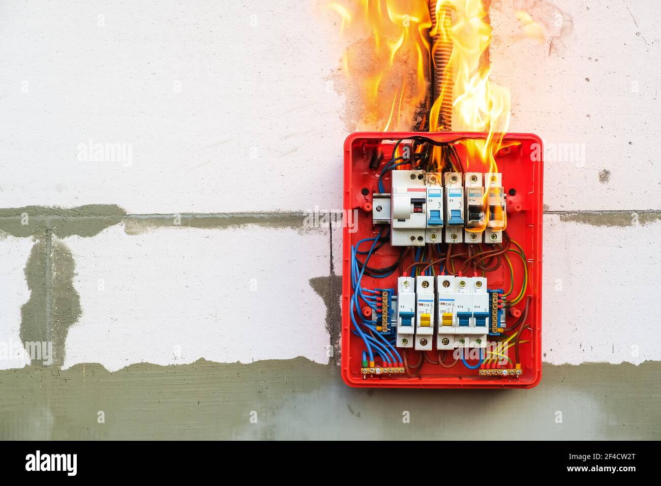 Burning switchboard from overload or short circuit on wall Stock Photo