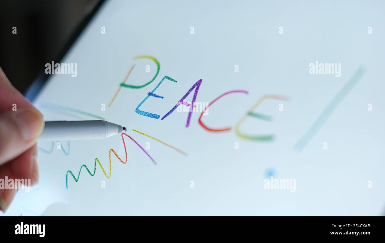 Woman hand view while digital writing peace word on a graphic tablet Stock Photo