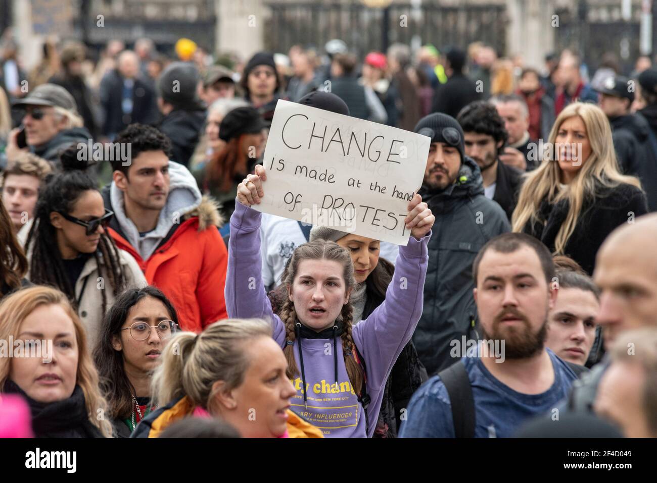 Westminster, London, UK. 20th Mar, 2021. Anti-lockdown protesters have gathered in London. Large numbers of protesters have marched around Westminster, bringing traffic to a standstill in Whitehall and Parliament Square. Female with placard stating change is made at the hands of protest Stock Photo