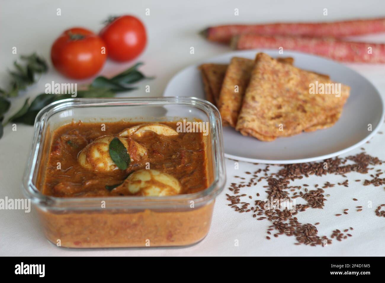 Boiled egg curry, a cashew tomato based gravy served along with whole wheat Indian flat bread made of grated carrots and powdered flax seed. Shot on w Stock Photo