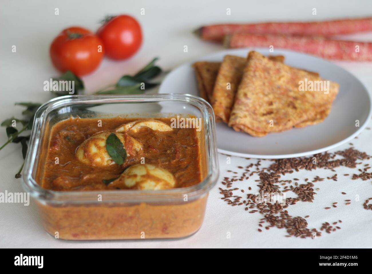 Boiled egg curry, a cashew tomato based gravy served along with whole wheat Indian flat bread made of grated carrots and powdered flax seed. Shot on w Stock Photo