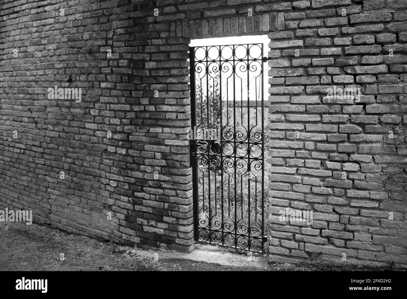 An iron gate of a secret garden with a brick wall (Marche, Italy, Europe) Stock Photo