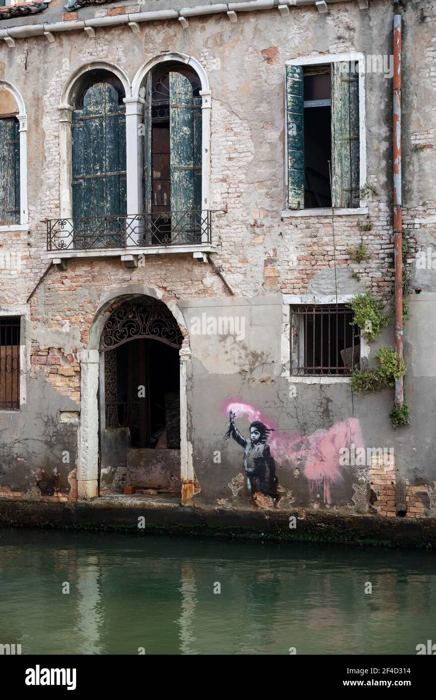 Venice. Italy. Banksy's artwork (May 2019) portraying a migrant child wearing a lifejacket while holding a pink flare, near Campo Santa Margherita in Stock Photo