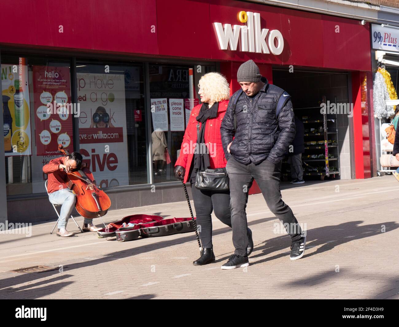 Wilko store shop with shoppers Walthamstow High Street, Waltham Forest, London, with busker playing the cello Stock Photo