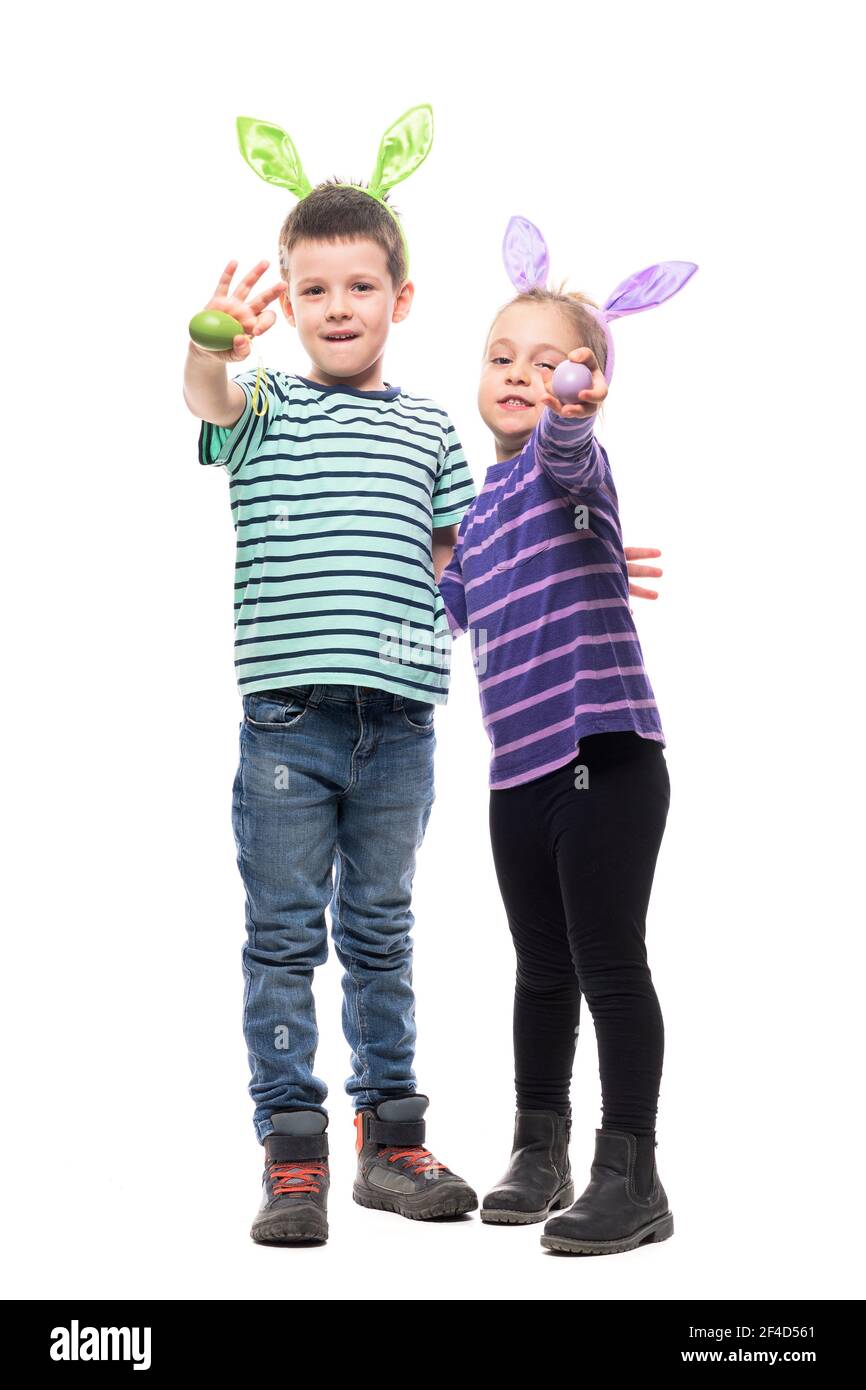Happy two kids boy and girl with bunny ears holding Easter eggs waving hello at camera. Full body isolated on white background Stock Photo
