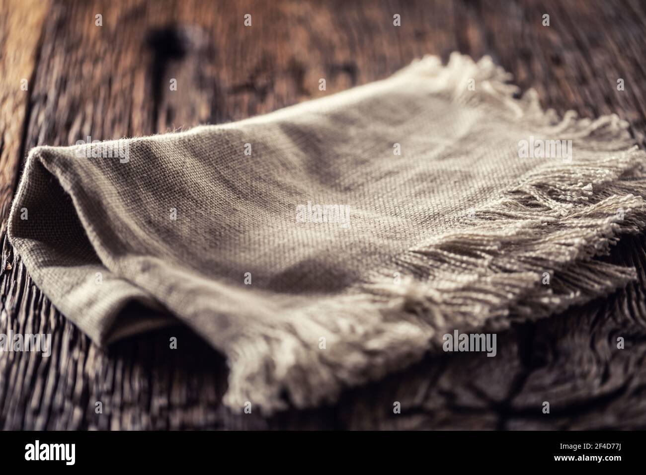 Flax or jute rustical rag folded on dark wooden table. Stock Photo