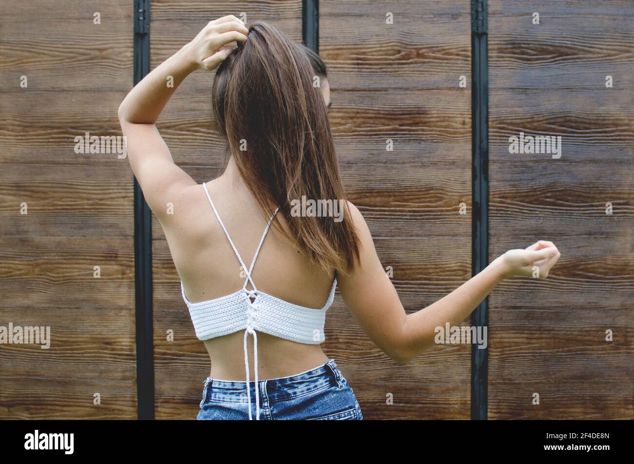 Rear view of a teenage girl standing outdoors touching her hair Stock Photo