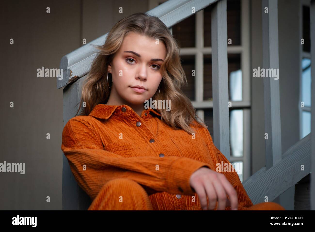 Portrait of a beautiful young woman sitting on a staircase in a hallway Stock Photo