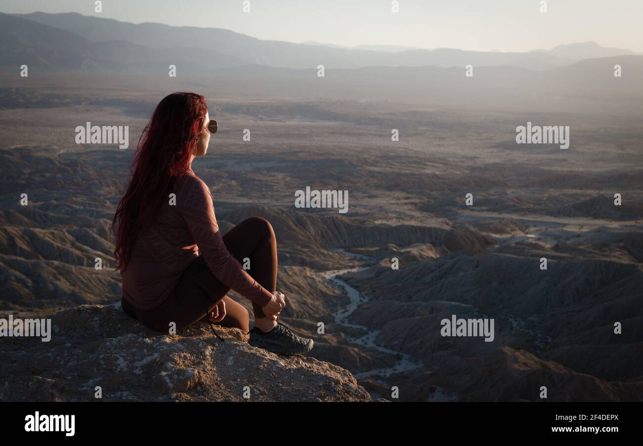 Woman sitting on mountain looking at badlands mountain view, Anza Borrego Desert State Park, California, USA Stock Photo