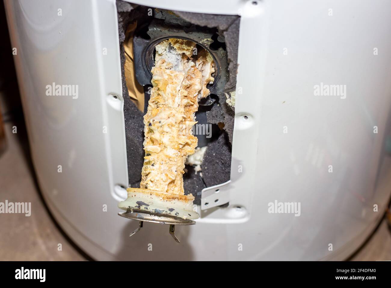 Repair and maintenance of boilers. A tubular electric heater covered with lime scale sticks out of the hole in the boiler. Stock Photo