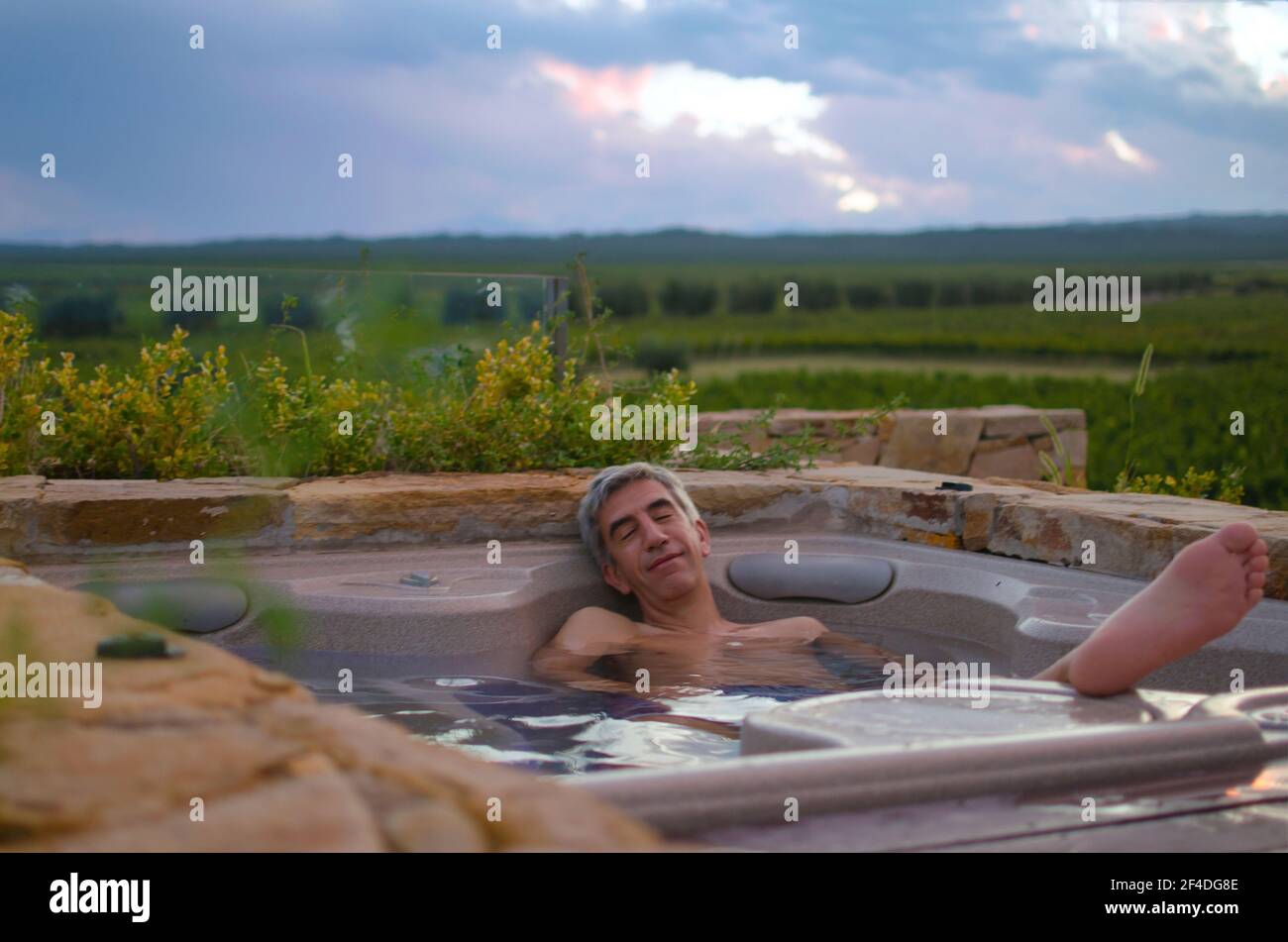 Smiling man relaxing in an outdoor jacuzzi in a garden, Argentina Stock Photo