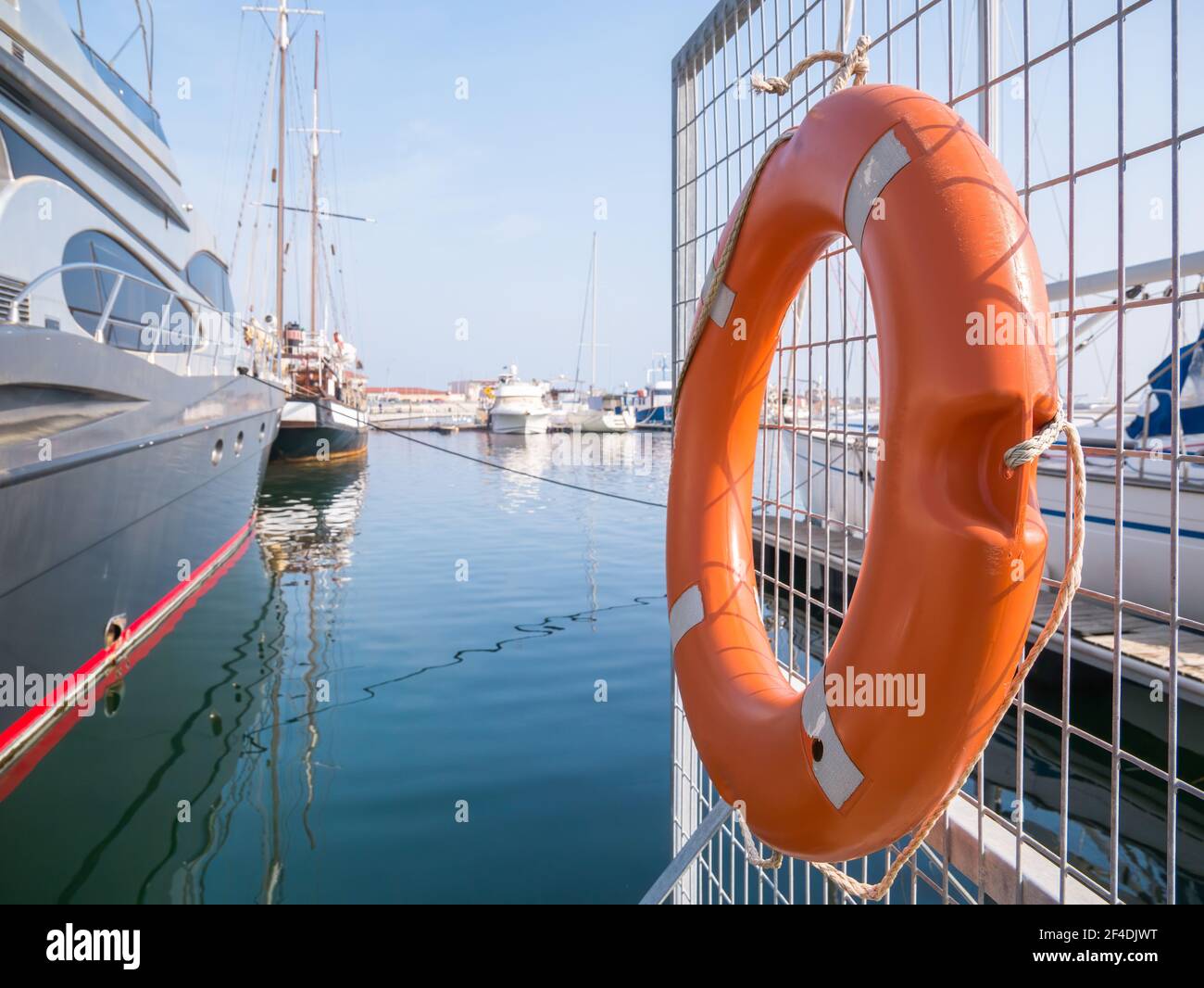 A lifebelt, lifebuoy, water wheely also known as Kisbee ring hanging from a fence at the harbour Stock Photo