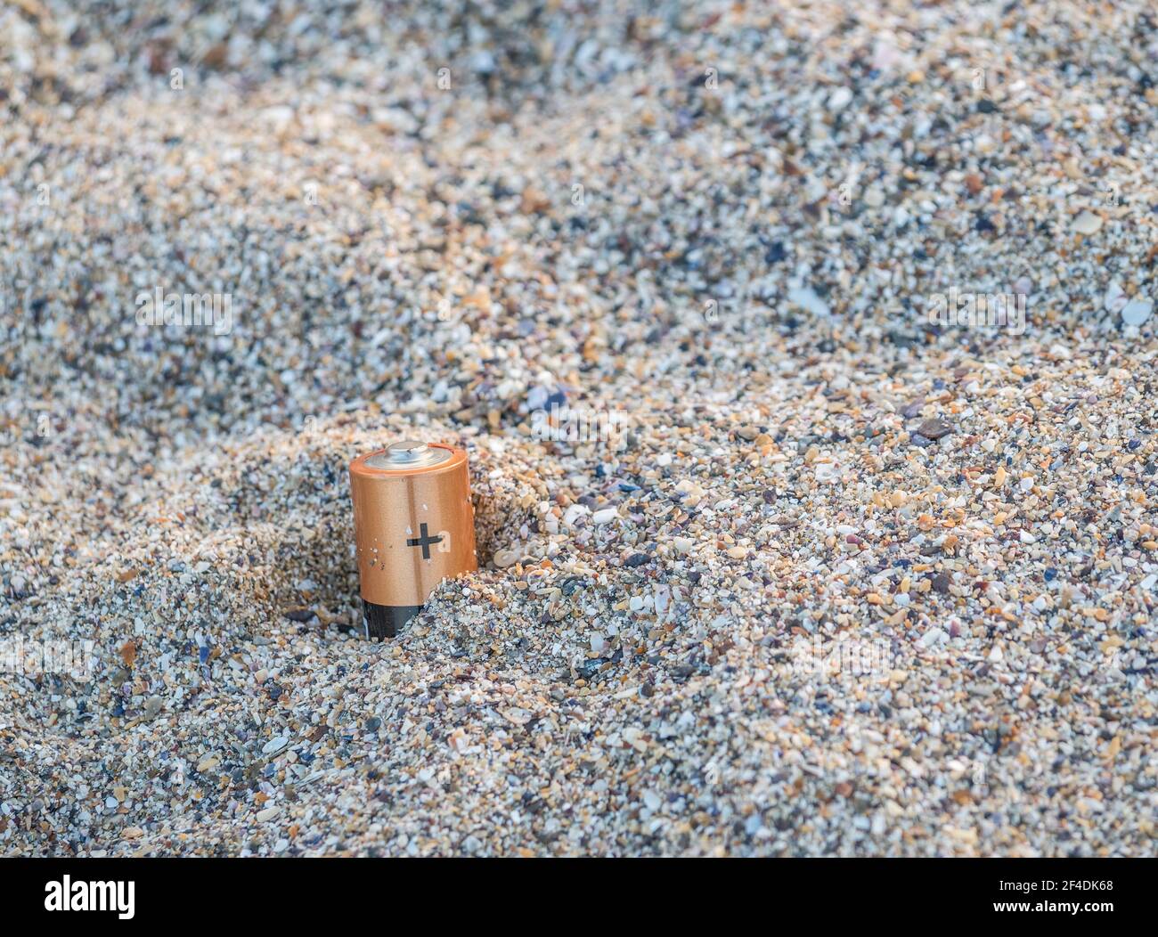 Improperly disposed batteries in the sand on the beach.Used waste batteries. Environmental pollution concept. Stock Photo