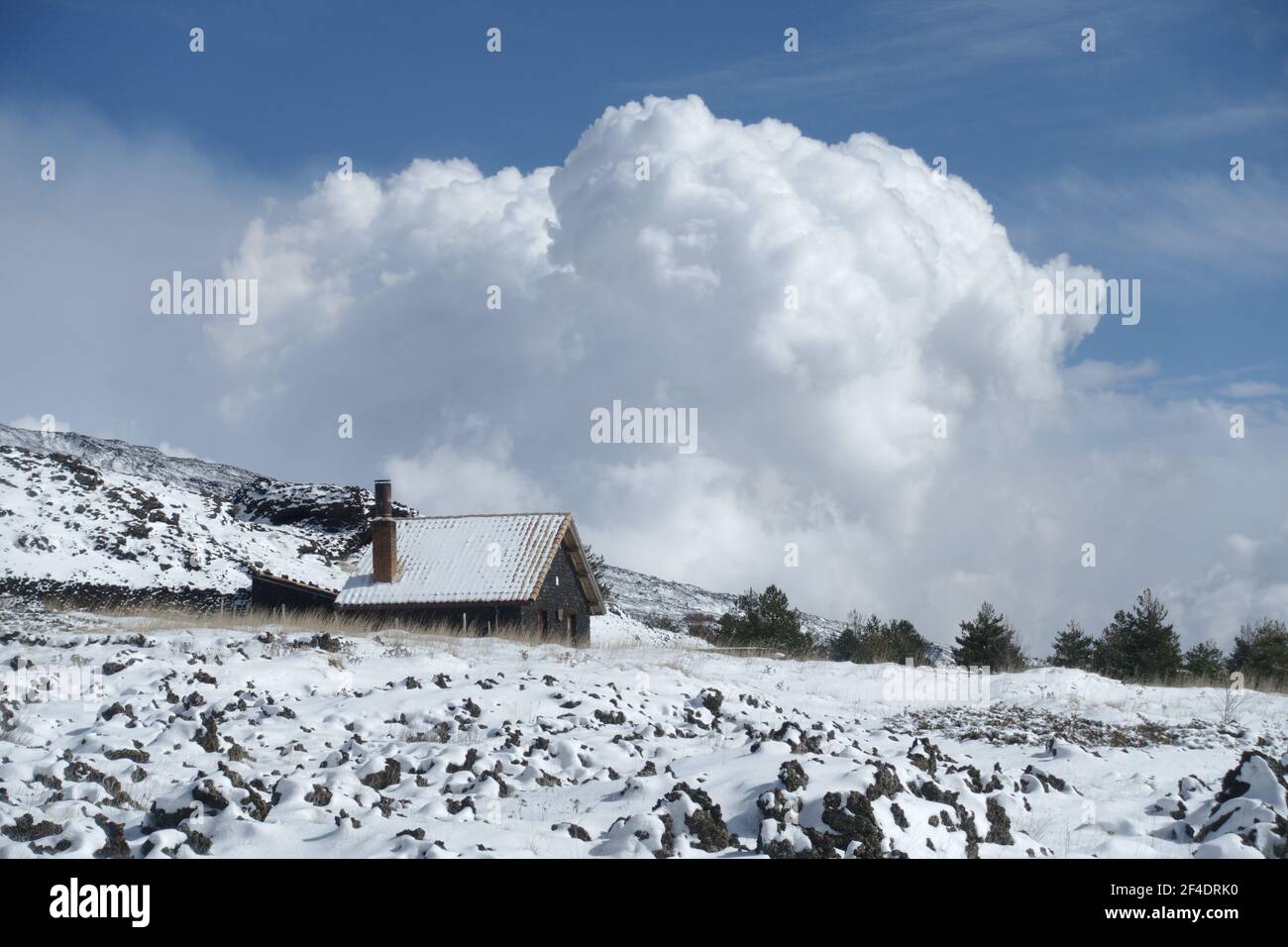 mountain stone refuge snow covered in Sicily on background a big white clouds in the blue sky of Etna Park Stock Photo