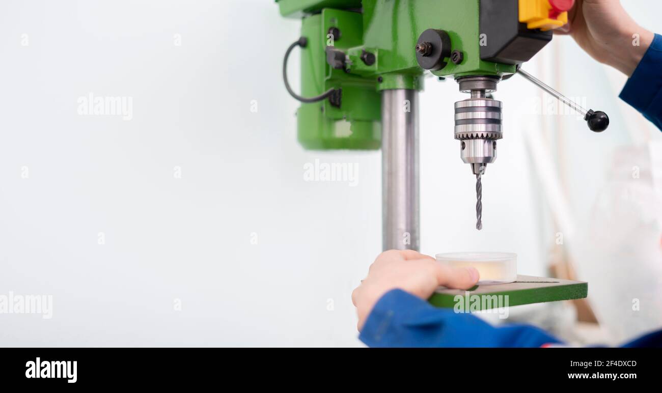 a close up young male worker using a drill machine on the factory Stock Photo