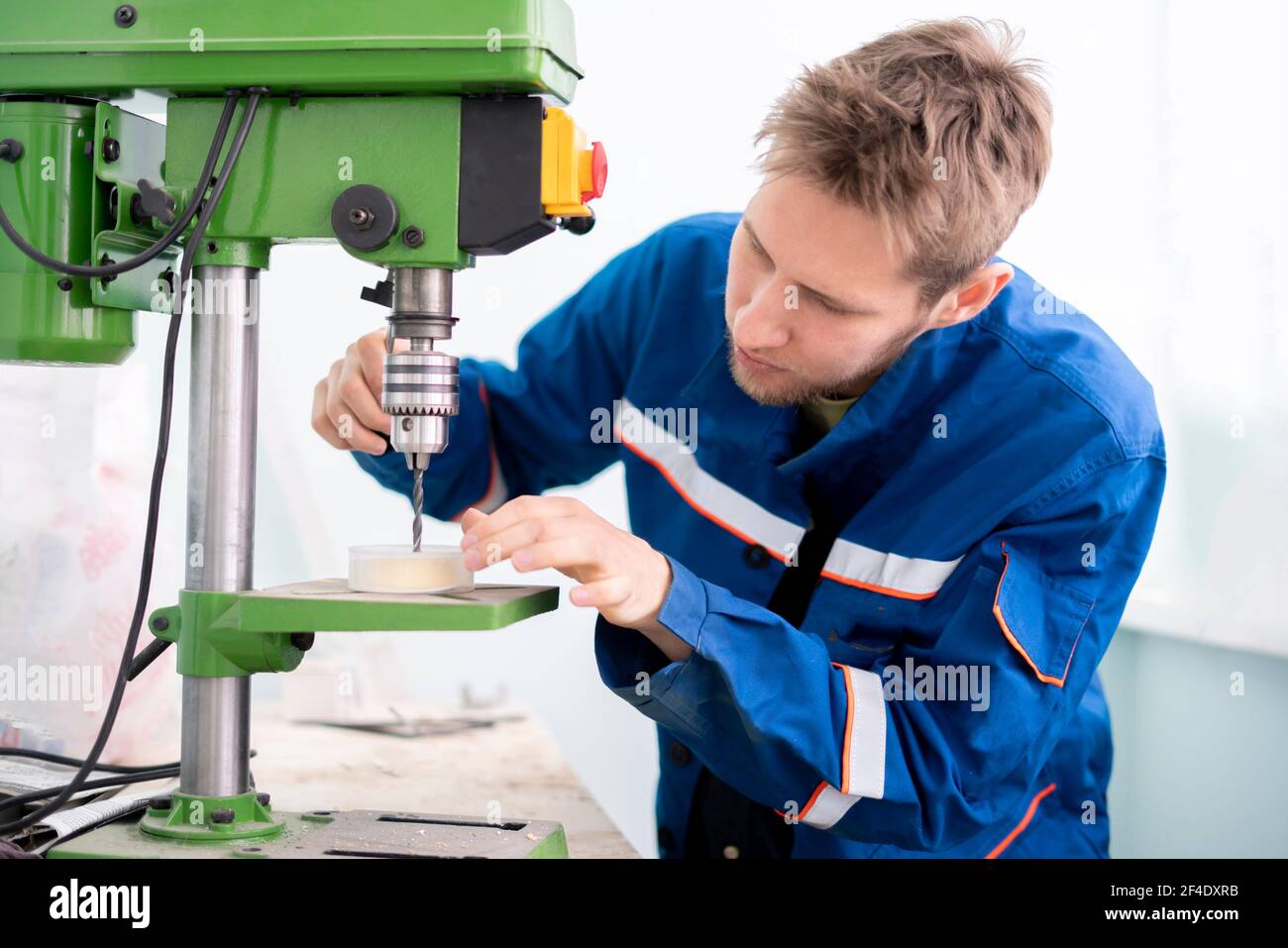 a close up young male worker using a drill machine on the factory Stock Photo
