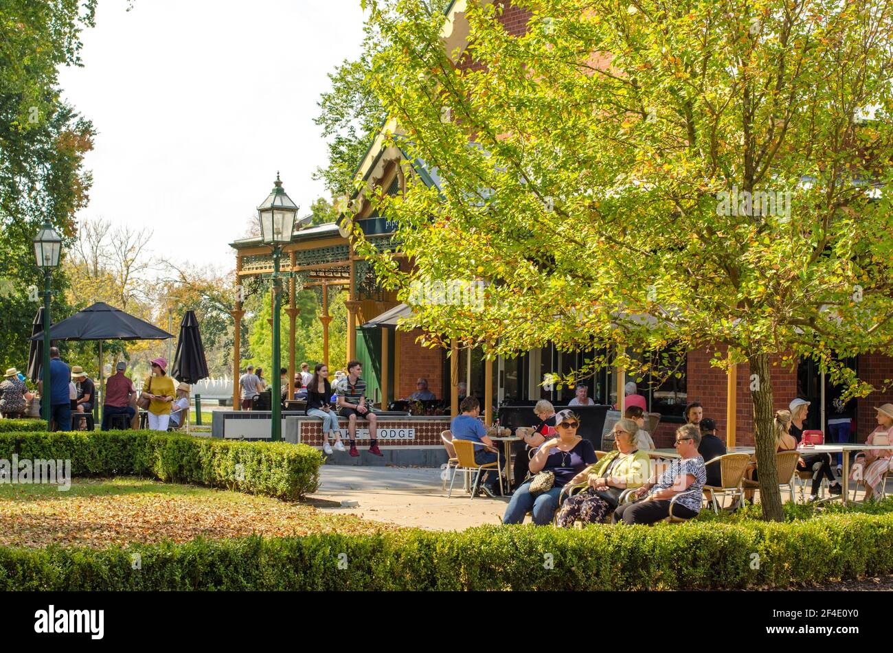 Tourists sitting outdoor at a restaurant with an old-world building, enjoying the relaxing environment and the beautiful autumn sunlight in Ballarat. Stock Photo
