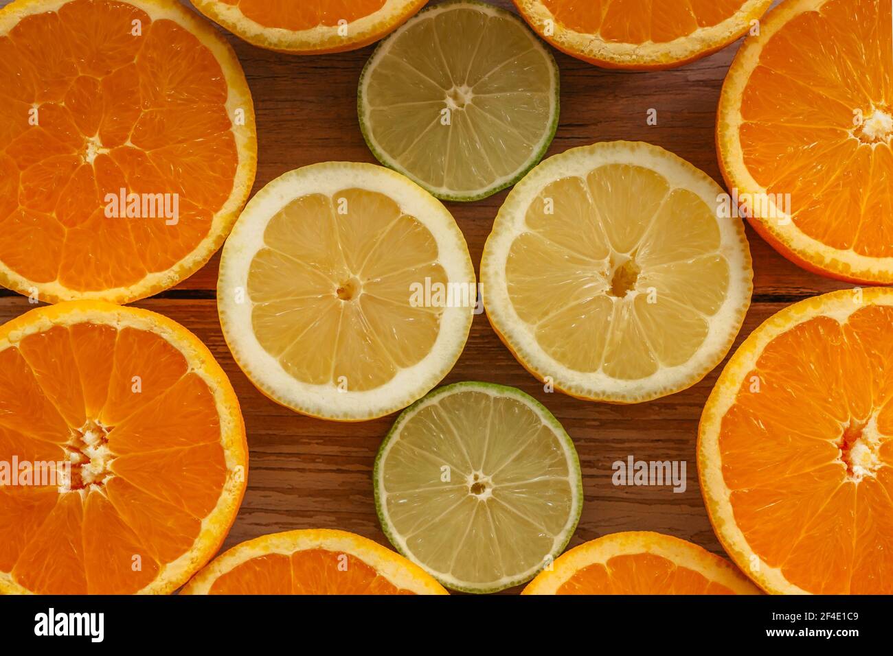 Oranges,limes and lemons slides on wooden table view from above. Beautiful background with fresh fruit half cut.Healthy eating vitamin C.Summer tropic Stock Photo