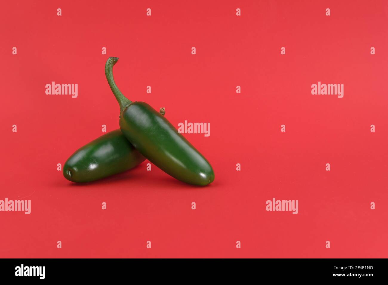 Ripe green chili peppers on a red background, the background has room to add text Stock Photo