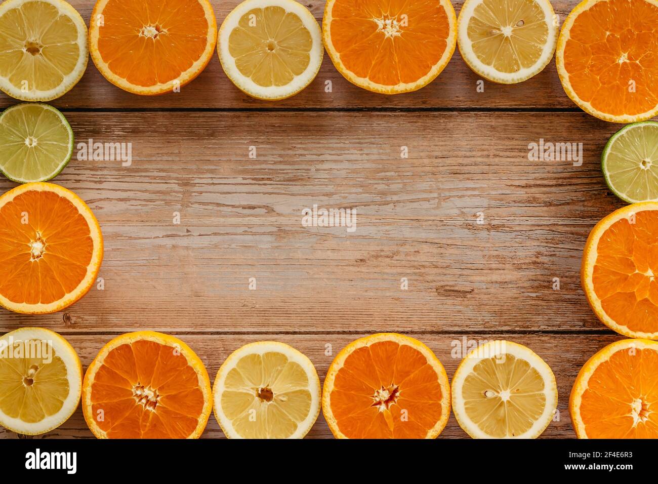 Oranges,limes and lemons slides on wooden table view from above.Beautiful background with fresh fruit half cut.Healthy eating vitamin C.Summer tropica Stock Photo