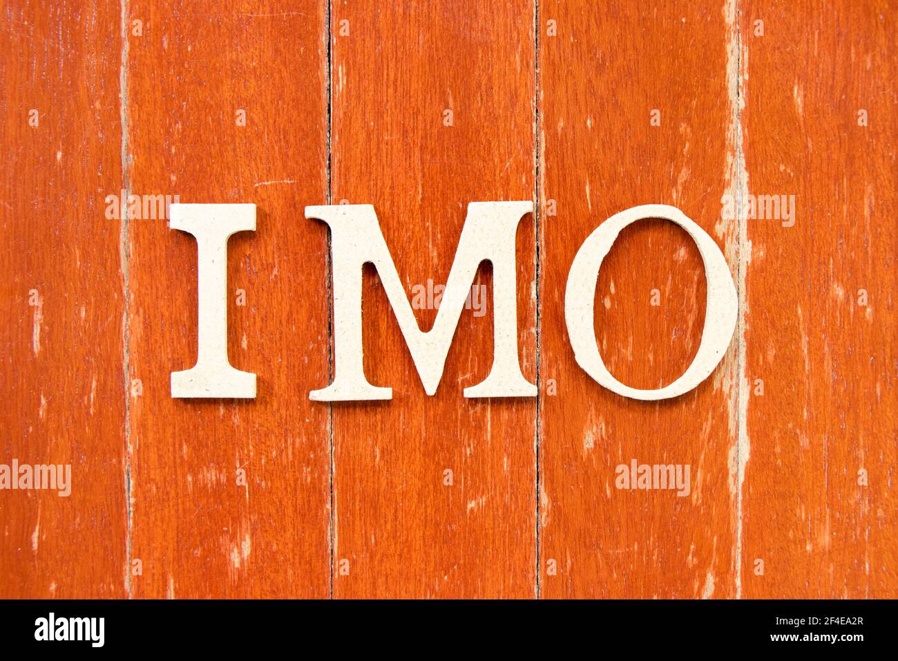 Alphabet letter in word IMO (Abbreviation of in my opinion) on old red  color wood plate background Stock Photo - Alamy