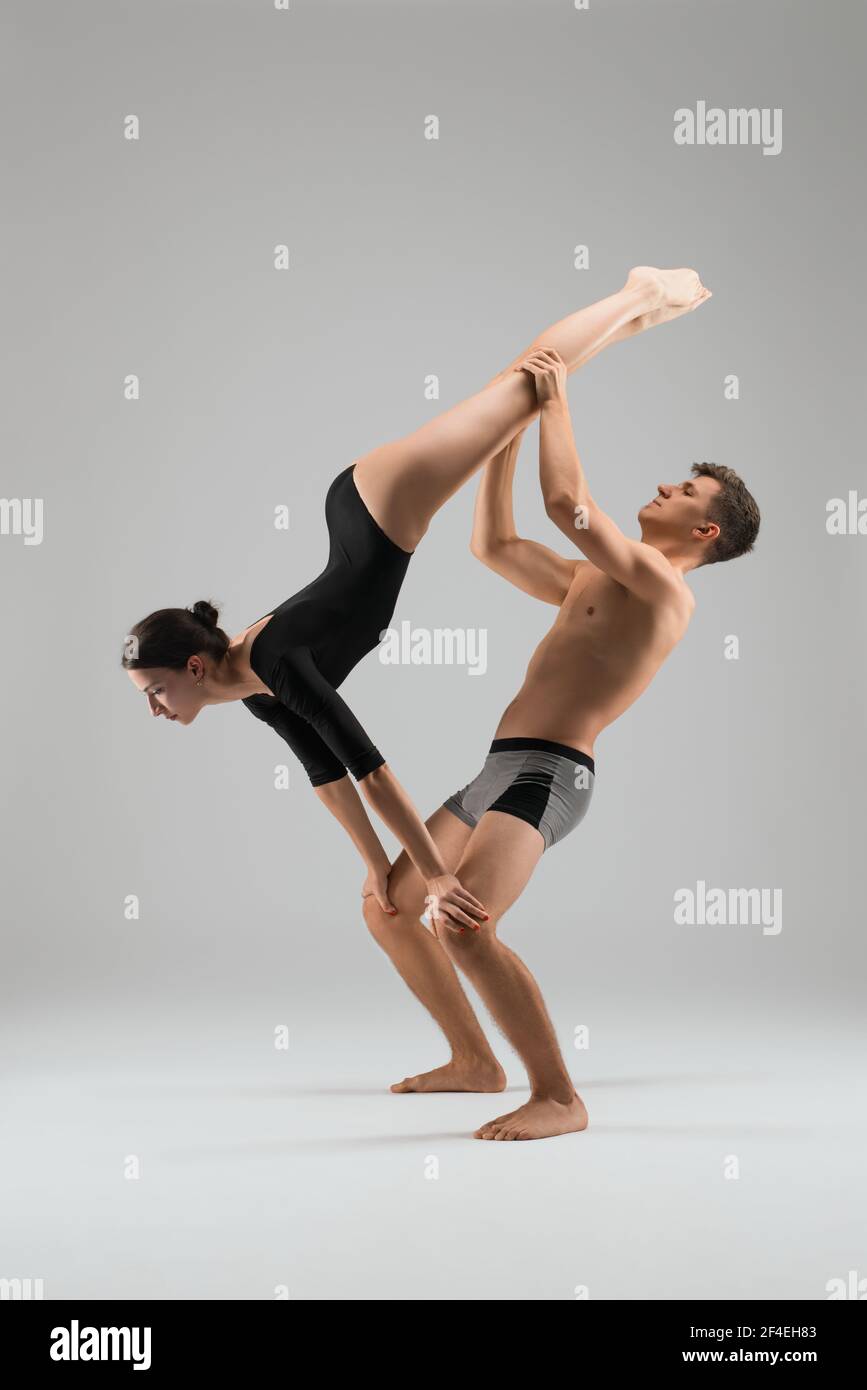 Couple of gymnasts performing acrobatic trick in studio Stock Photo