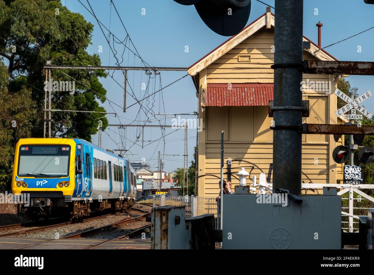 Pedestrians wait as a train passes through a railway crossing in Clifton Hill, Melbourne, Victoria, Australia. Stock Photo