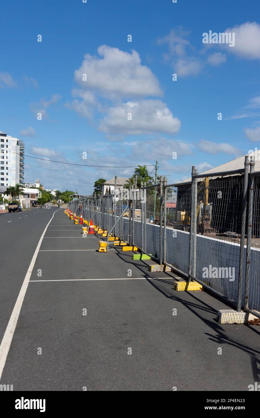 A line of temporary fencing with yellow concrete bases erected in front of a demolition site in a regional city. Stock Photo