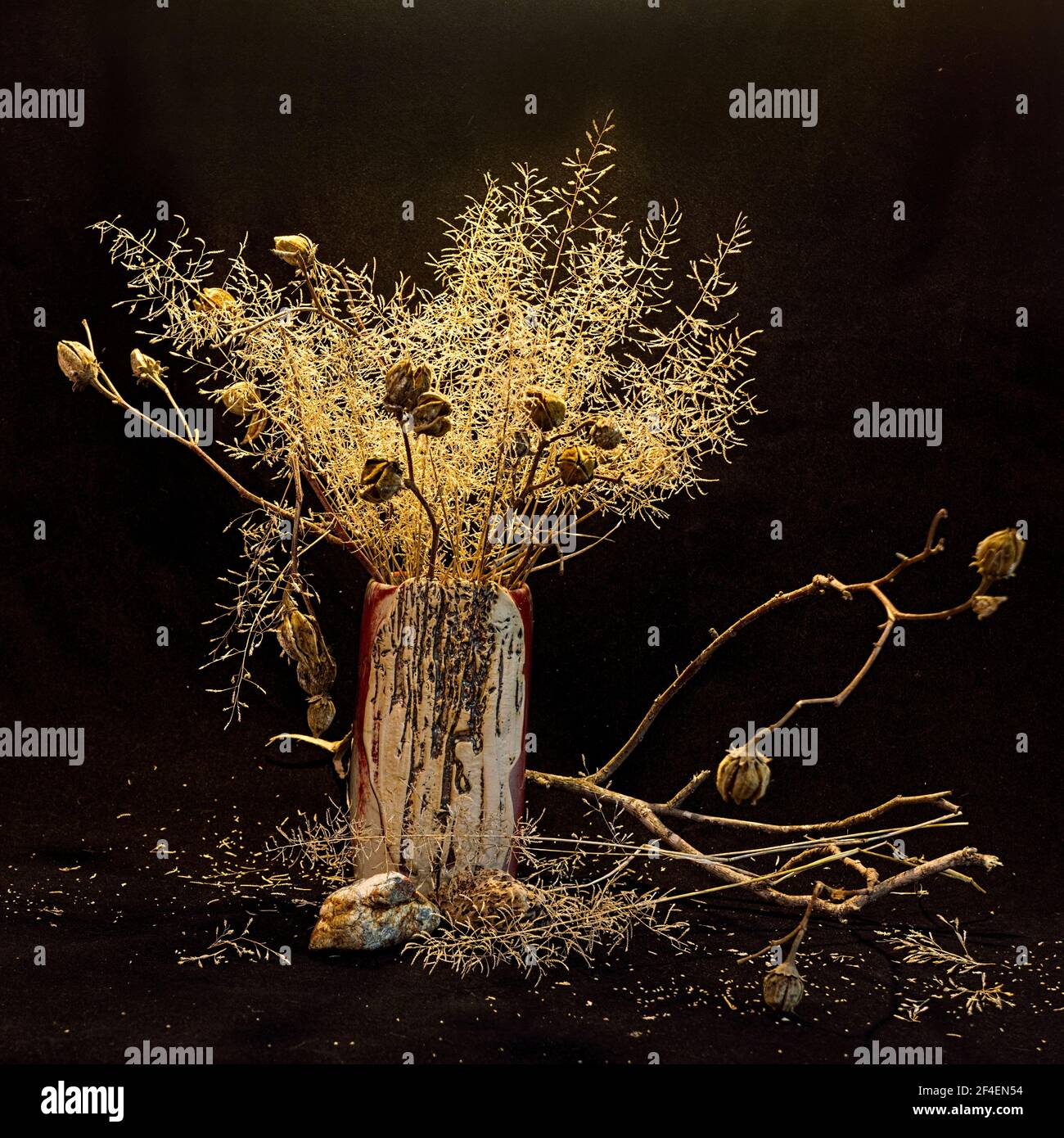 Wild native grass and seed pods in a rustic vase against a grungy textured dark backgound. Stock Photo