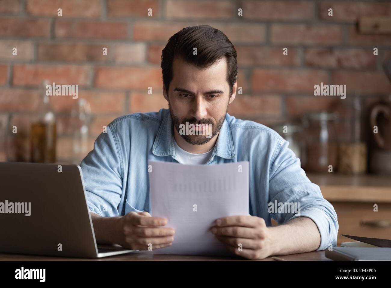Serious man work on computer reading paperwork Stock Photo