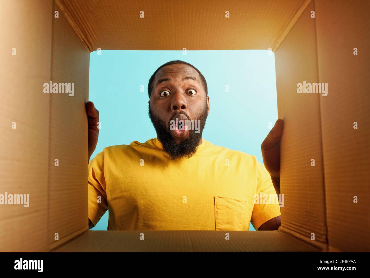 Happy man receives a package from online shop order. happy and surprised expression. Blue background. Stock Photo