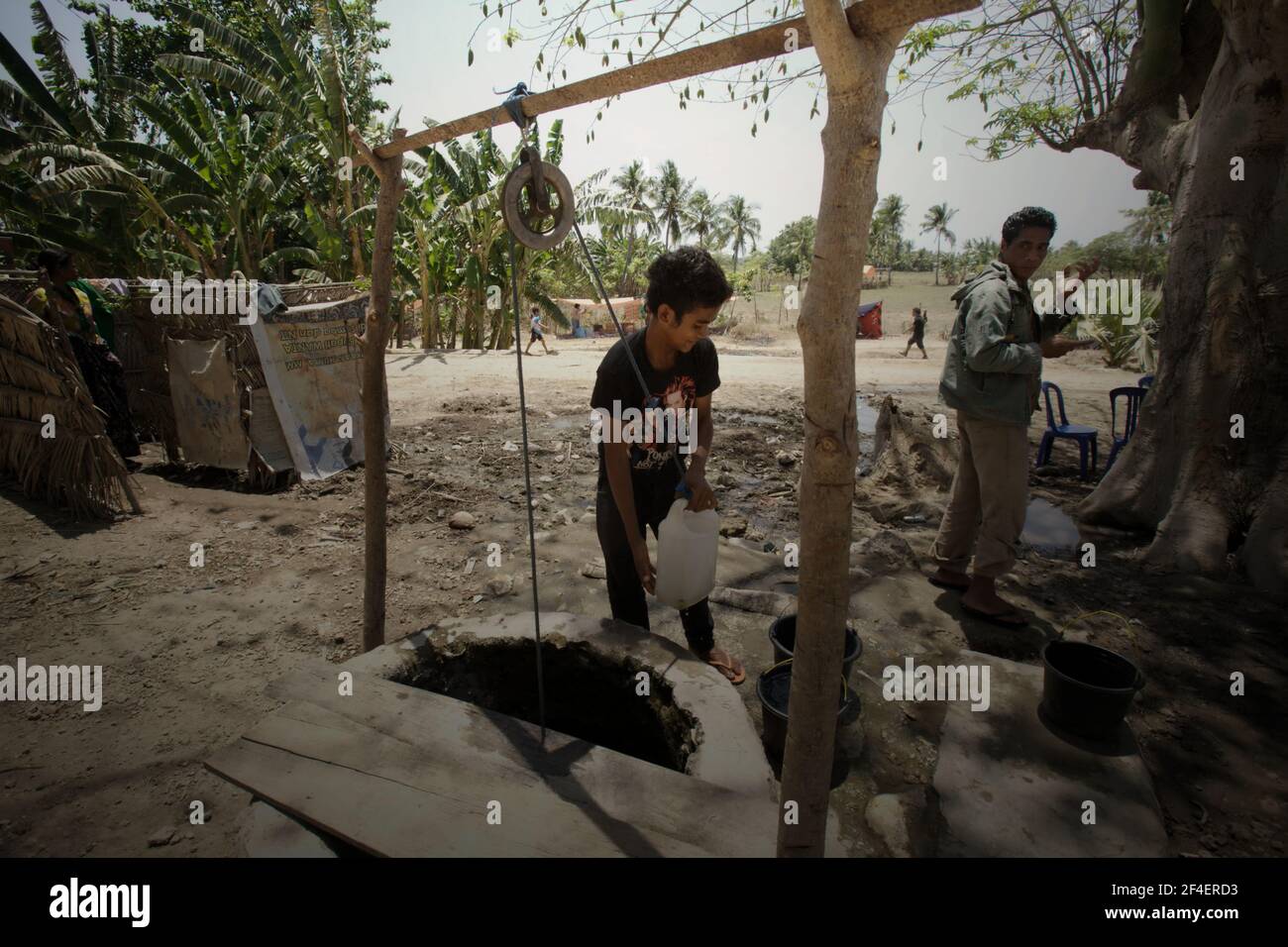 A young man taking water from a communal water well in Kawangu, Sumba, a dry island in East Nusa Tenggara, Indonesia. According to UN Water in their Summary Progress Update 2021, which published on March 1, 2021 in Geneva, 4.2 billion people or 55% of the world's population lacked safely managed sanitation services, and 3 billion people or 40% of the world's population lacked a basic handwashing facility with soap and water in 2017. Stock Photo